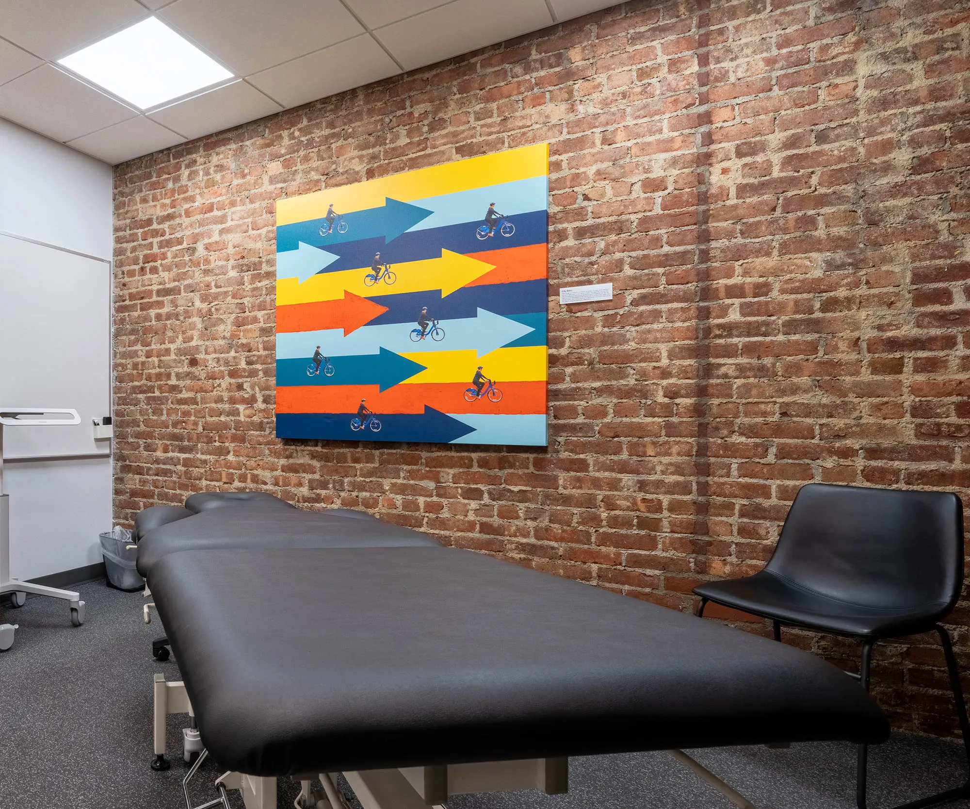 Treatment room with a bright fish-pattern mural on exposed brick.