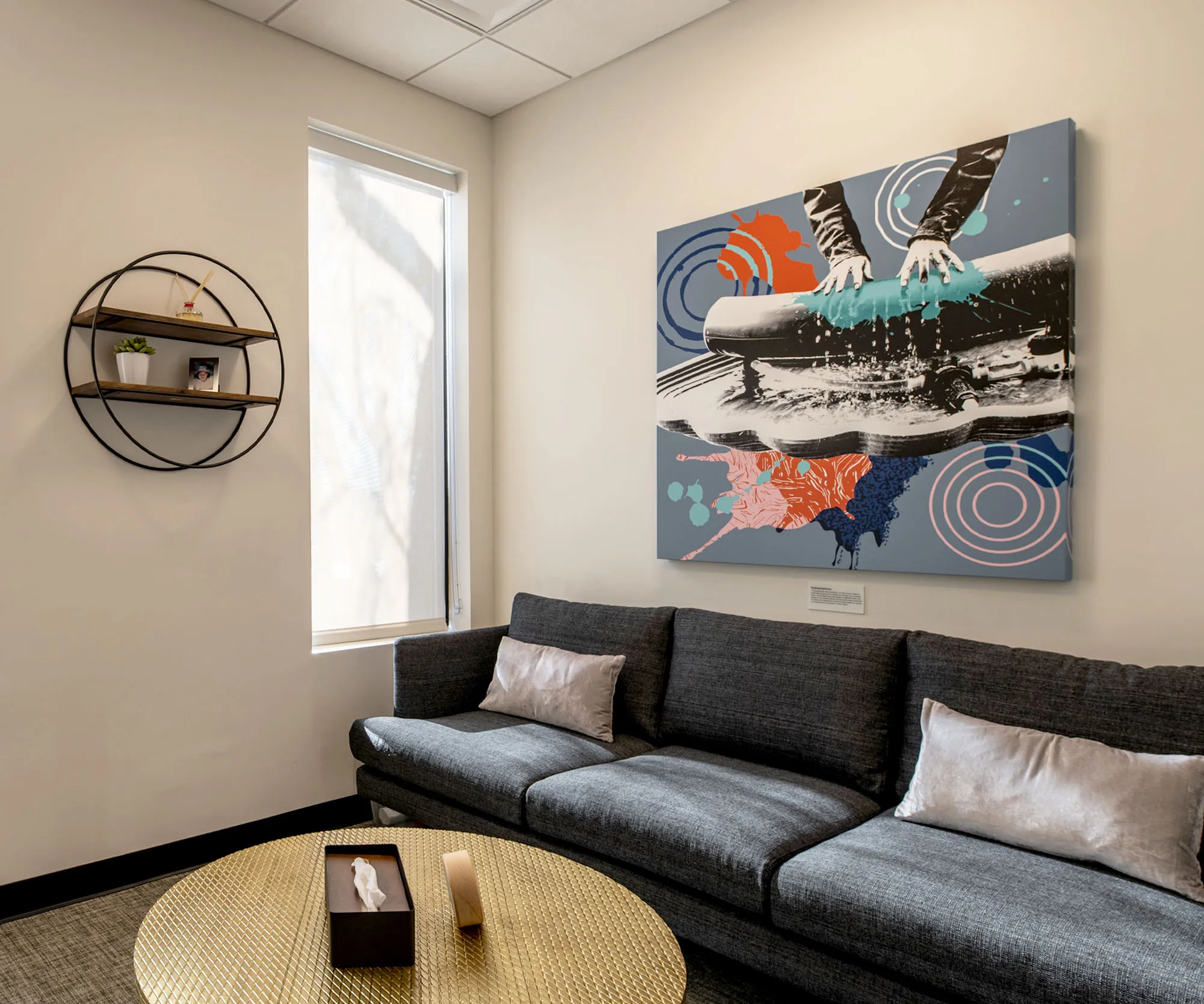Clinic lounge with a mountain-scene artwork above the sofa.
