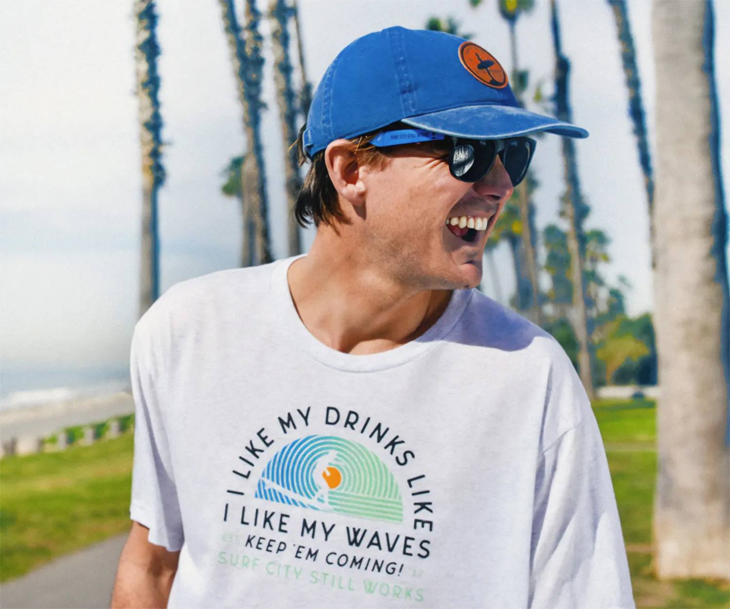 Man laughing in a tee reading "I like my drinks like I like my waves".