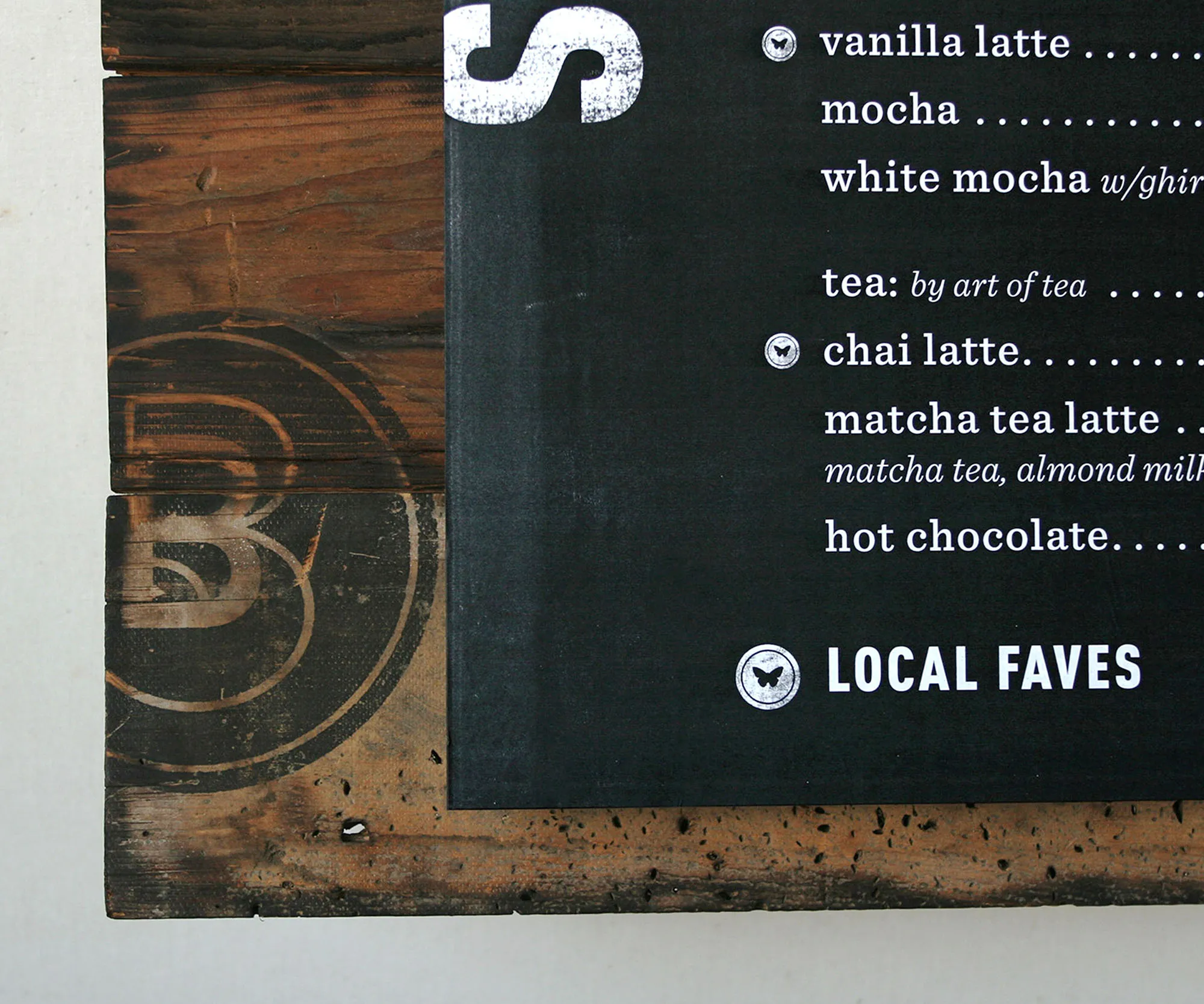 Menu detail listing lattes and teas beside the monogram.