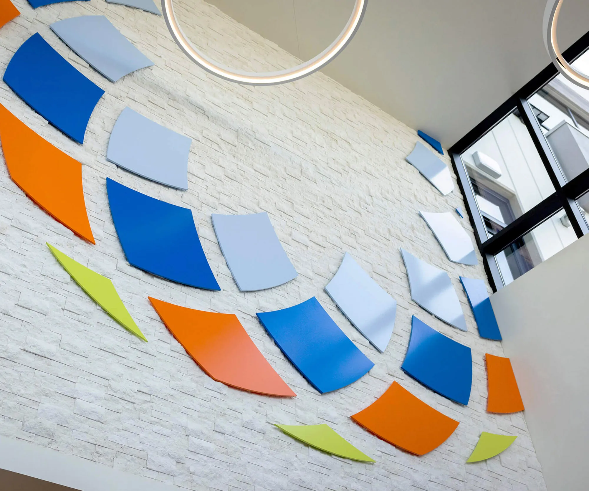 Interior wall installation of the BeWell mosaic logo in coloured tiles.