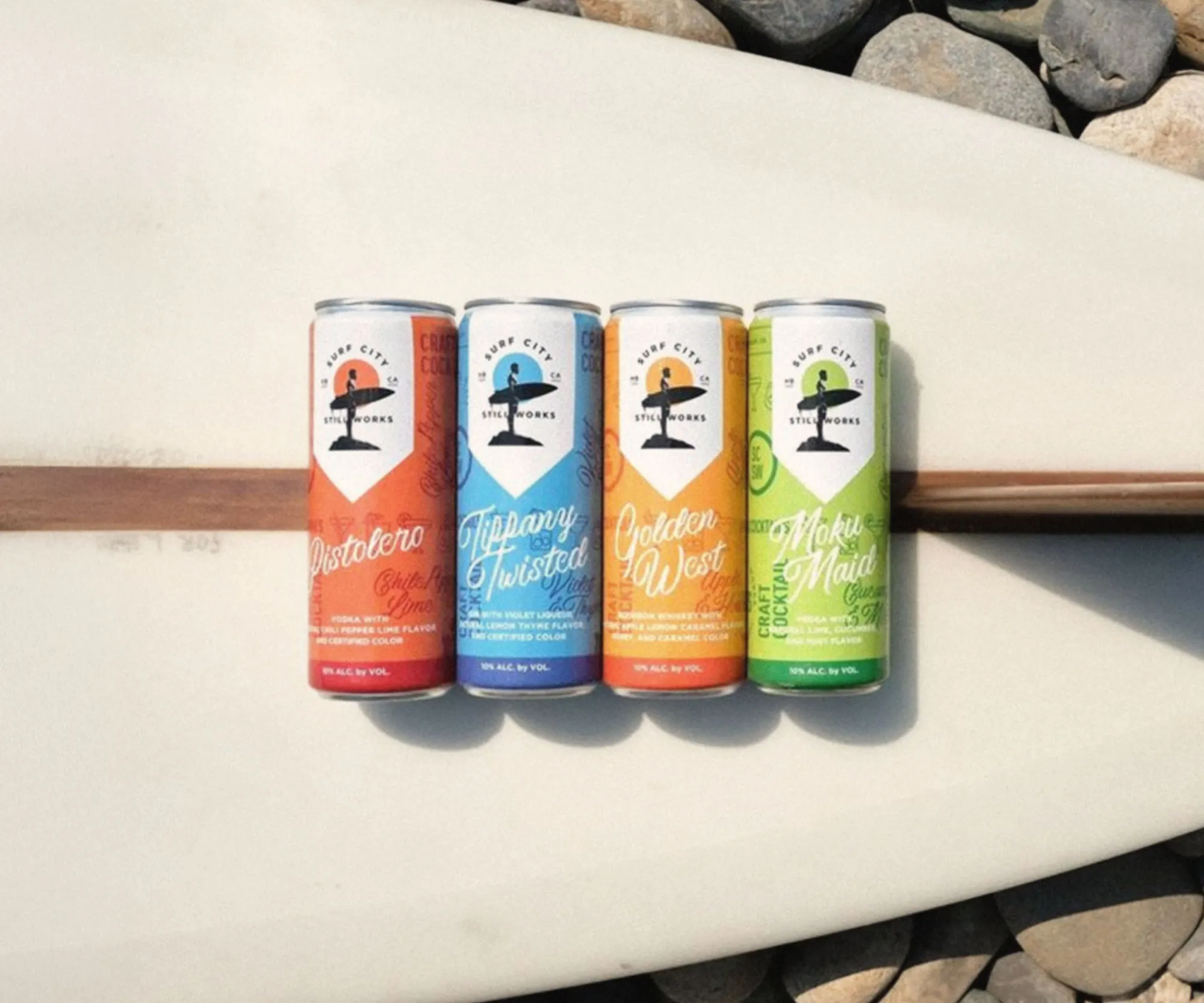 Four hard seltzer flavours lined up along a surfboard.